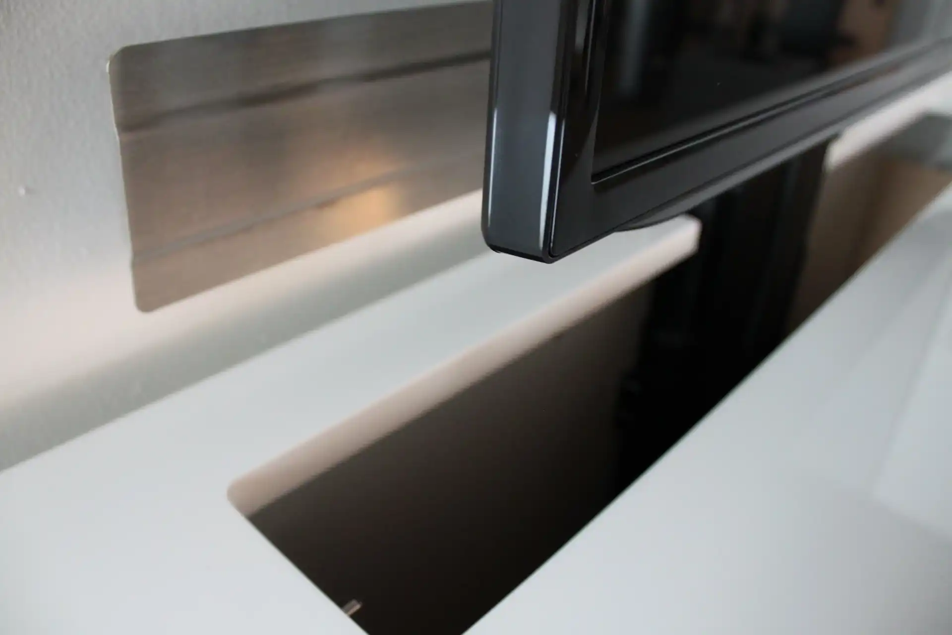 A hole in a cabinet with a TV lift inside with a lid to cover the whole