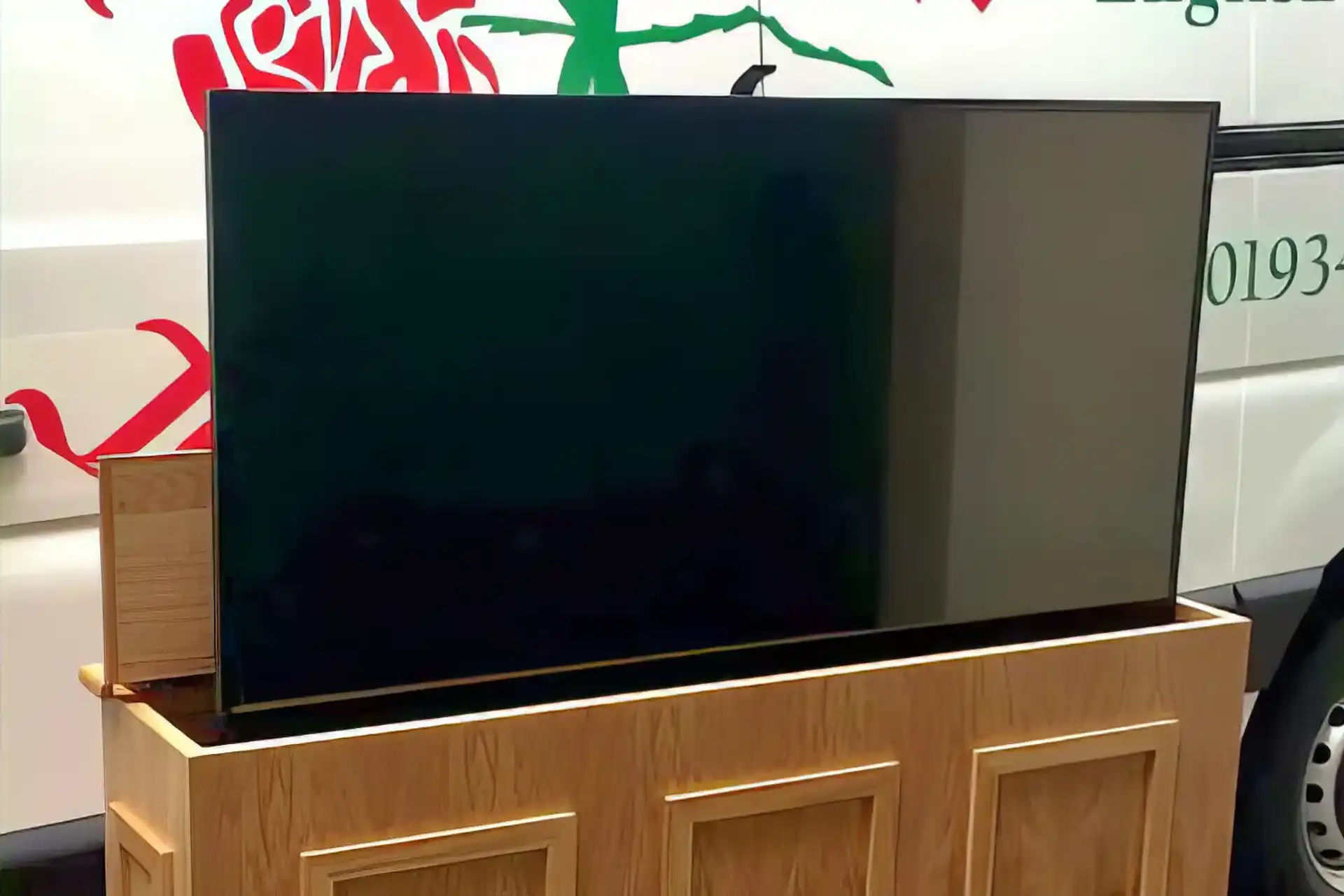 A TV emerging from a custom built cabinet infront of a van
